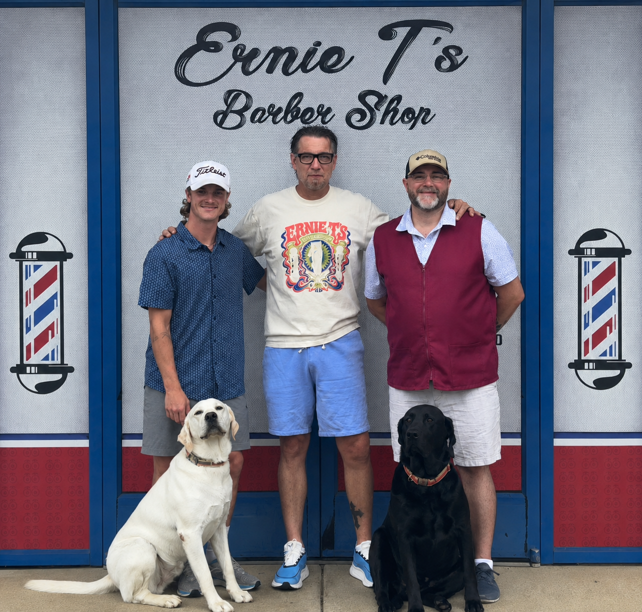Ernie Thomas and crew with two dogs outside Ernie T’s Barber Shop